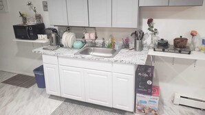Una cocina con armarios blancos, encimera de granito, un fregadero, estufa y diversos utensilios de cocina.