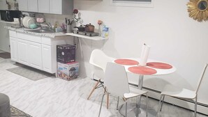 Una cocina moderna con armarios blancos, horno empotrado y comedor con mesa y sillas blancas.