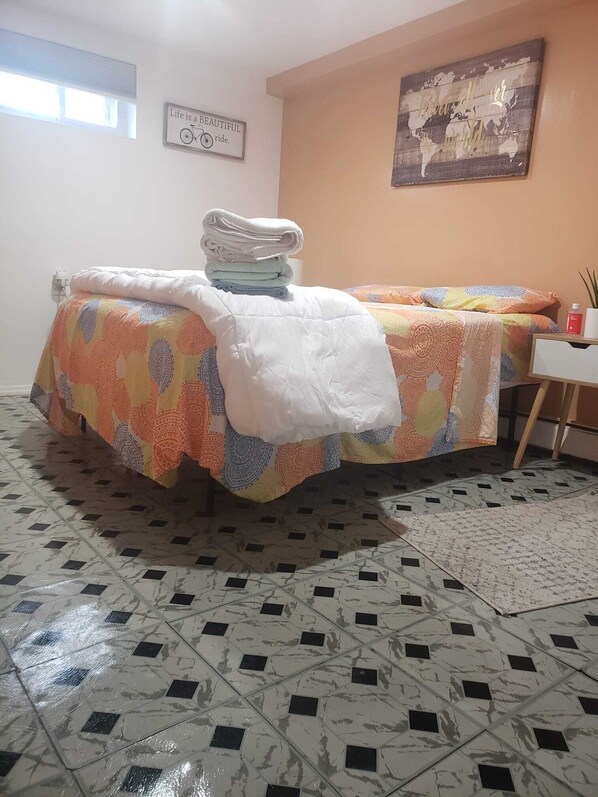 A room with a bed, a small desk, a wall with a map, and a window.