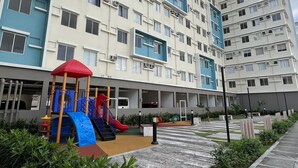 Un immeuble résidentiel à plusieurs étages doté d’un espace de jeux pour enfants comprenant des toboggans et des structures d’escalade.