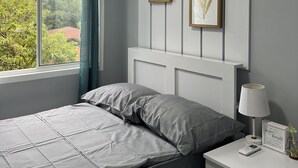 Une chambre à coucher avec un lit, une table de chevet, une lampe et deux tableaux encadrés accrochés au mur.