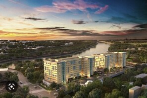 Et moderne hotelkompleks med flere bygninger, en parkeringsplads og en flod i baggrunden.