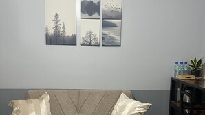 Un salon avec un canapé, une table basse ornée d’une plante et un mur sur lequel sont accrochées trois images encadrées.