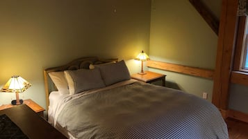 A bedroom with a bed, two bedside lamps, a wooden headboard, and a window.
