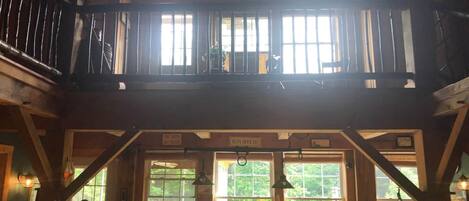 Een rustiek houten interieur met een eethoek, grote ramen en een balkon.