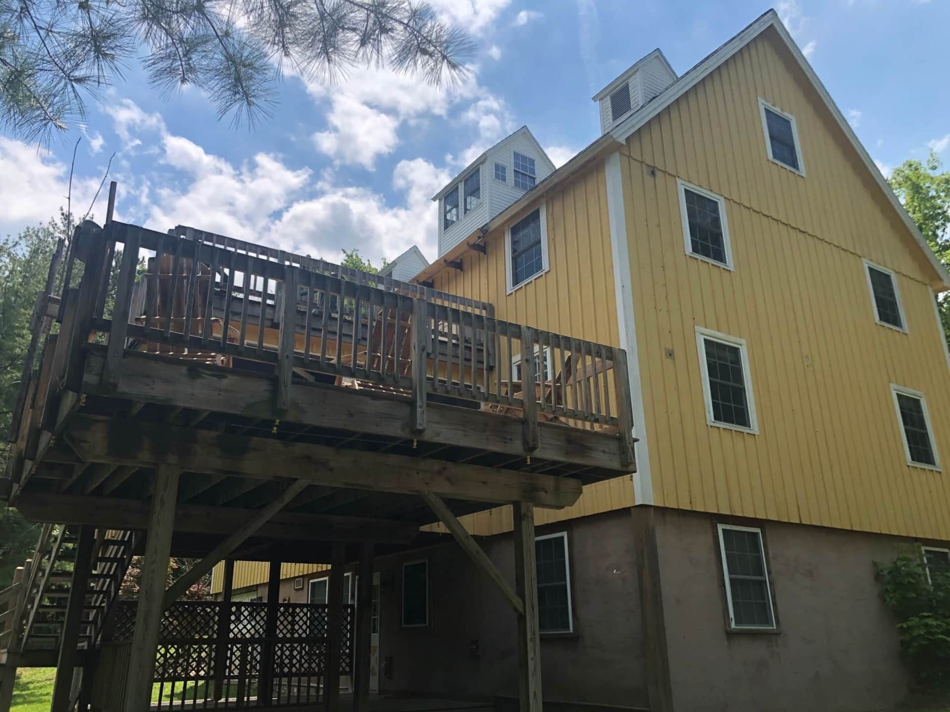 A two-story building with a wooden deck and a covered area.
