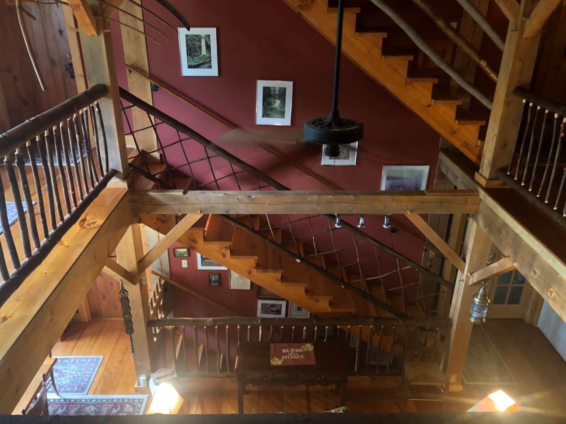 A wooden staircase with a red wall and framed pictures.