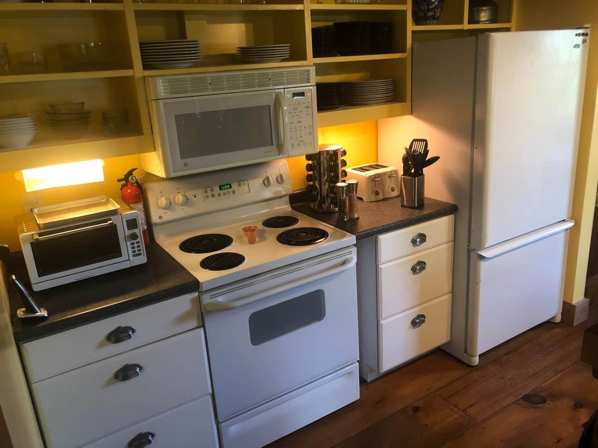 Une cuisine compacte équipée d’un four à micro-ondes, d’une cuisinière, d’un grille-pain et d’un réfrigérateur.