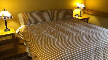 A neatly made bed with striped bedding, two bedside lamps, and a wooden nightstand.