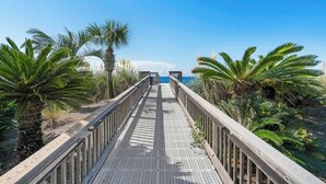 Un muelle de madera que conduce a una playa bordeada de palmeras.