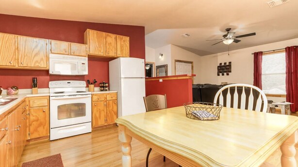 Una cocina compacta con armarios de madera, un refrigerador blanco, una estufa y una mesa de comedor con sillas.