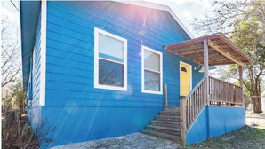 Una casa azul con un porche de madera y una puerta amarilla.