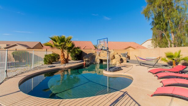 Una piscina amb una roca, palmeres i gandules.