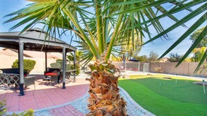 Un porxo amb seients exteriors, una palmera i un jardí ben cuidat.