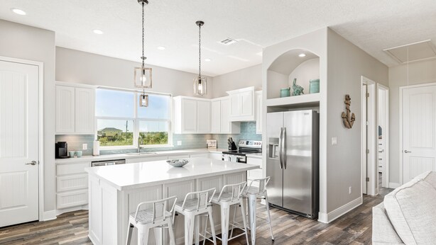 A modern kitchen with white cabinetry, a large island with bar stools, stainless steel appliances, and a view to the outdoors. - Beach View Retreat w/ Huge Covered Patio + Games (Bolivar Peninsula)