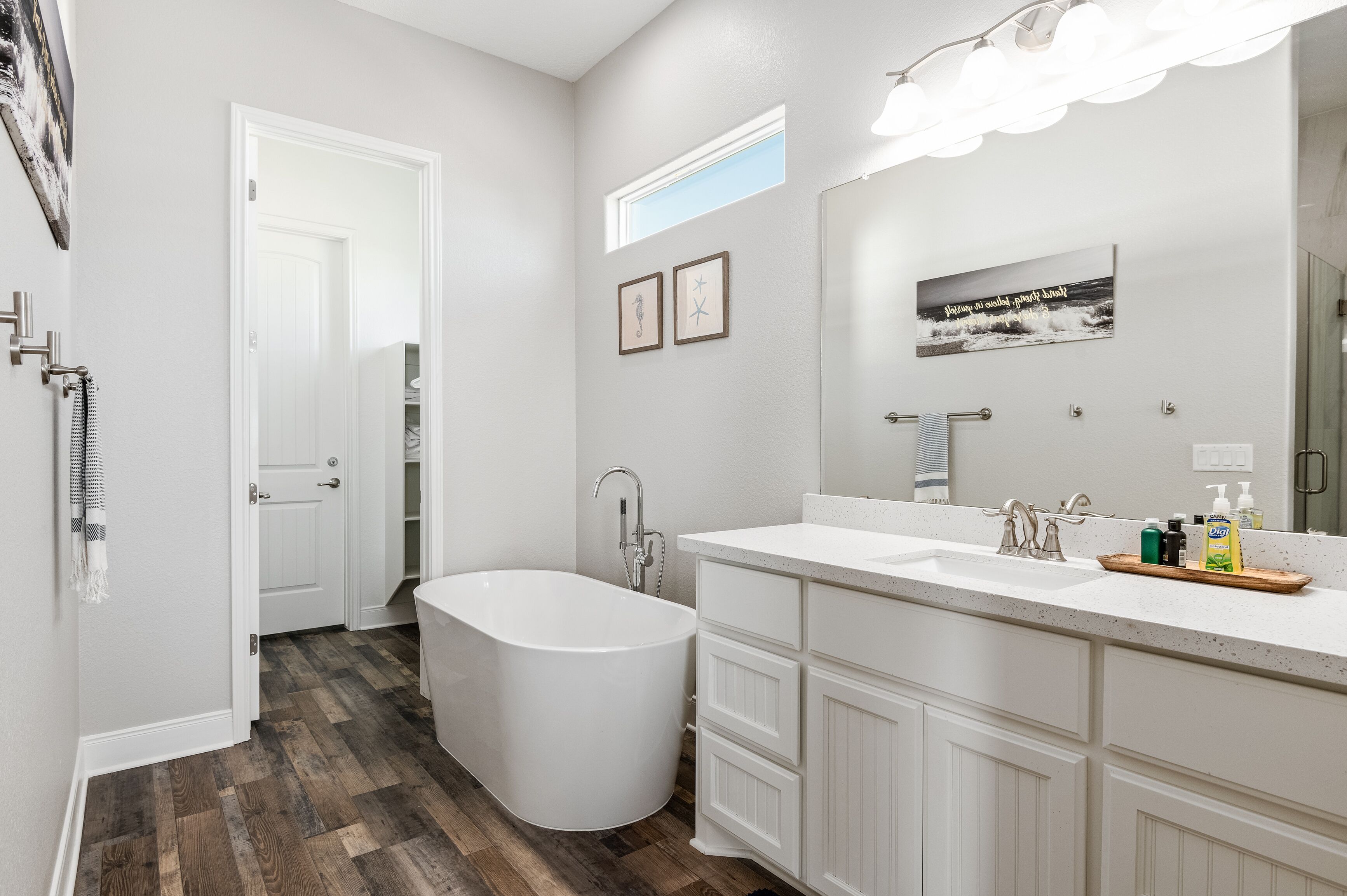 A modern bathroom with a freestanding bathtub, a large vanity with a mirror, and a shower area.