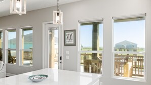 A kitchen with a large island, white countertops, and a view of the beach through large windows. - Beach View Retreat w/ Huge Covered Patio + Games (Bolivar Peninsula)