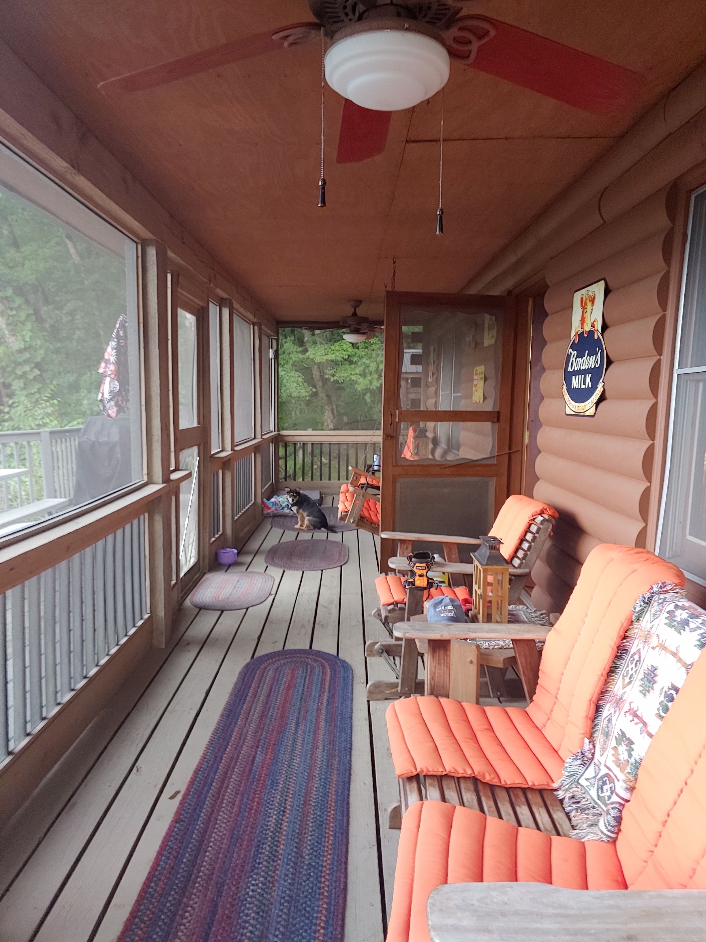 Eine Holzterrasse mit einer Couch, einem Tisch und einem Deckenventilator.