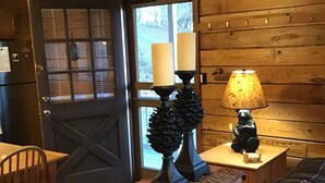 L’intérieur d’un chalet accueillant, avec une porte en bois, une table éclairée par des bougies, une lampe et un canapé en cuir.