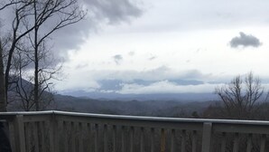 Un bain à remous sur une terrasse en bois, avec une vue imprenable sur les montagnes en arrière-plan.