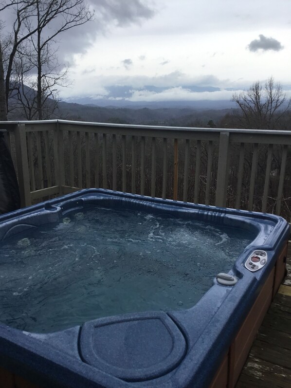 A hot tub on a wooden deck with a mountainous view in the background.