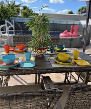A patio table with colorful bowls and a potted plant. - Elegant beautiful house w/pool 10 min from Miami Int. Airport (Hialeah)
