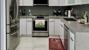 A modern kitchen with stainless steel appliances, white cabinetry, and a central island. - Elegant beautiful house w/pool 10 min from Miami Int. Airport (Hialeah)