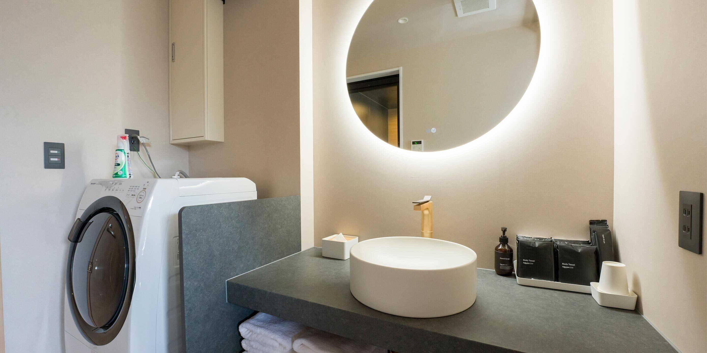 Une salle de bain moderne avec un miroir rond, un lavabo et un lave-linge.