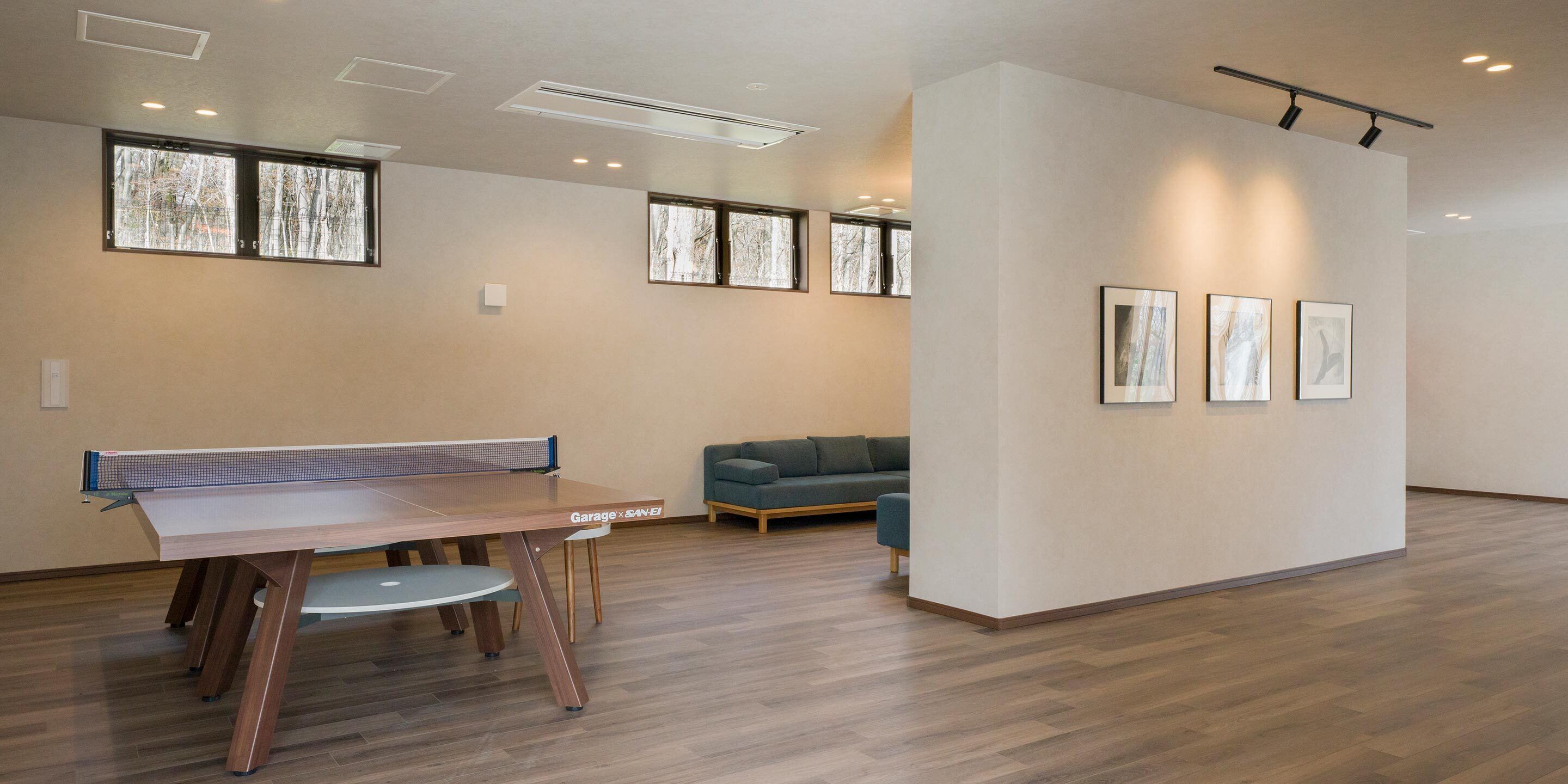 A spacious room with a ping pong table, a sofa, and framed artwork on the wall.