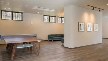 A spacious room with a ping pong table, a sofa, and framed artwork on the wall.
