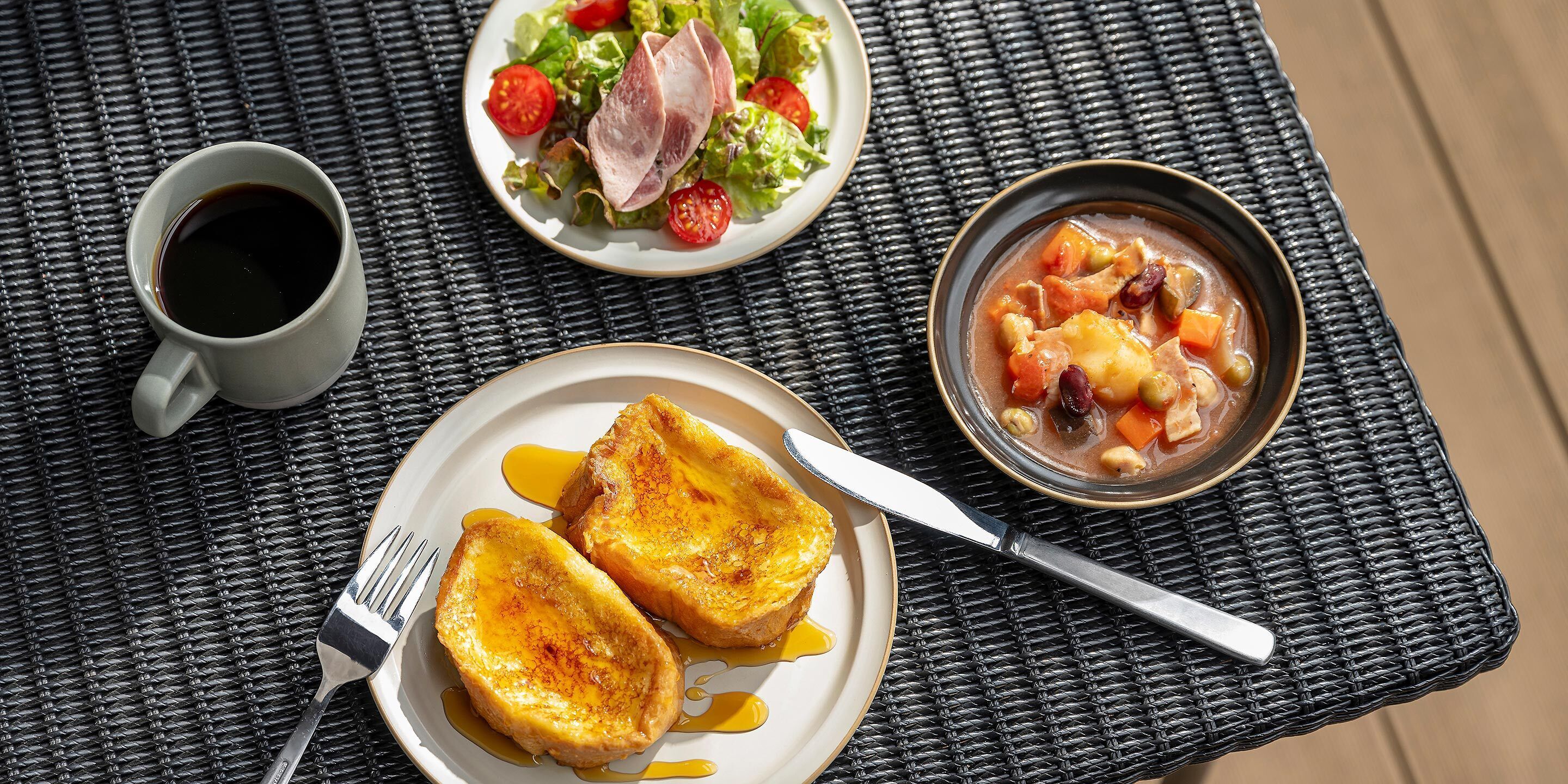 A table with a plate of toast, a bowl of soup, and a cup of coffee.