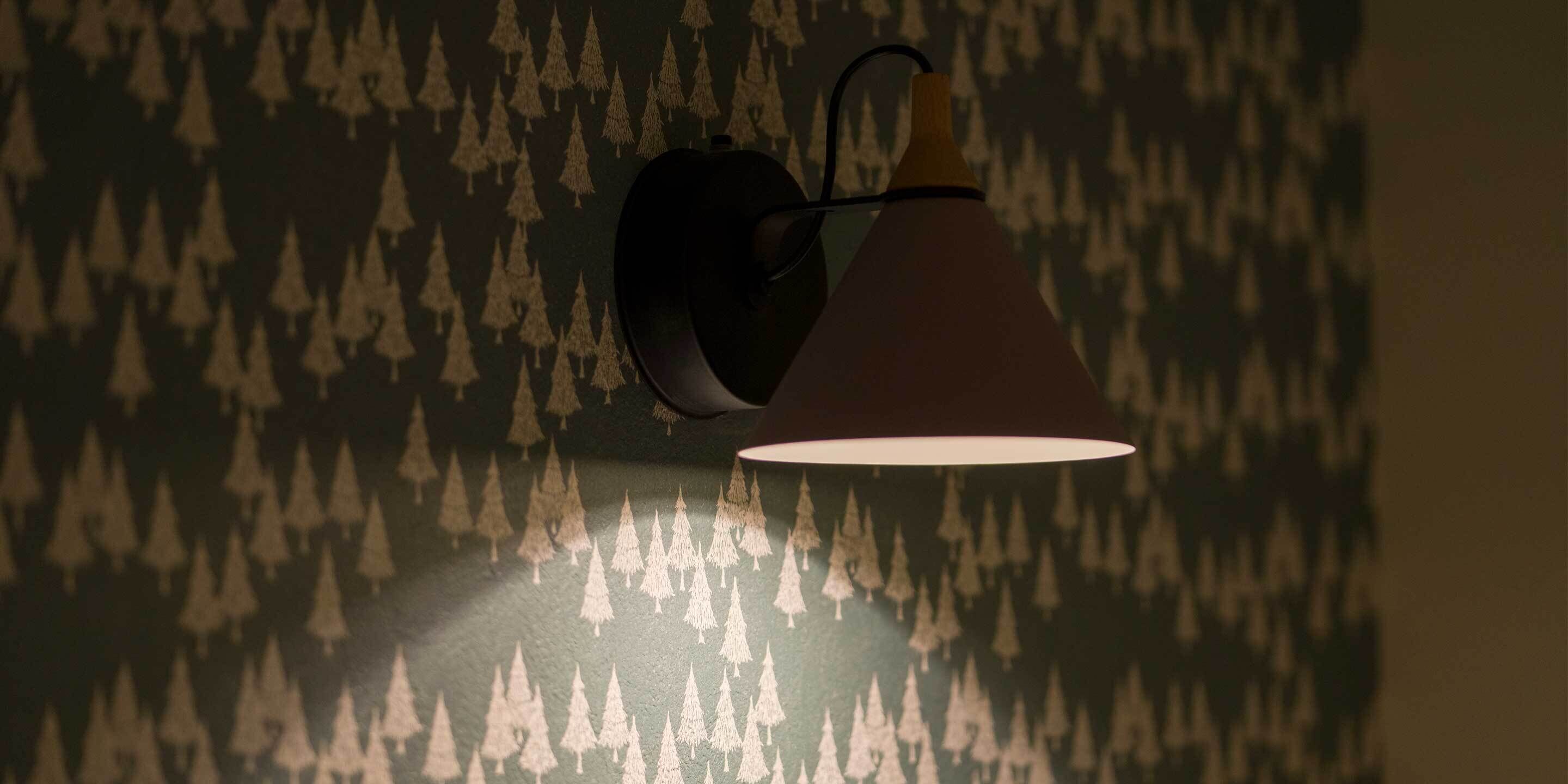 Una pared con un diseño de árboles y una lámpara de pared.