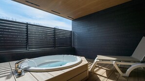 A modern outdoor hot tub area with a wooden deck, a lounge chair, and a view of the sky through a window. - Rakuten STAY VILLA Nasu (Nasu)