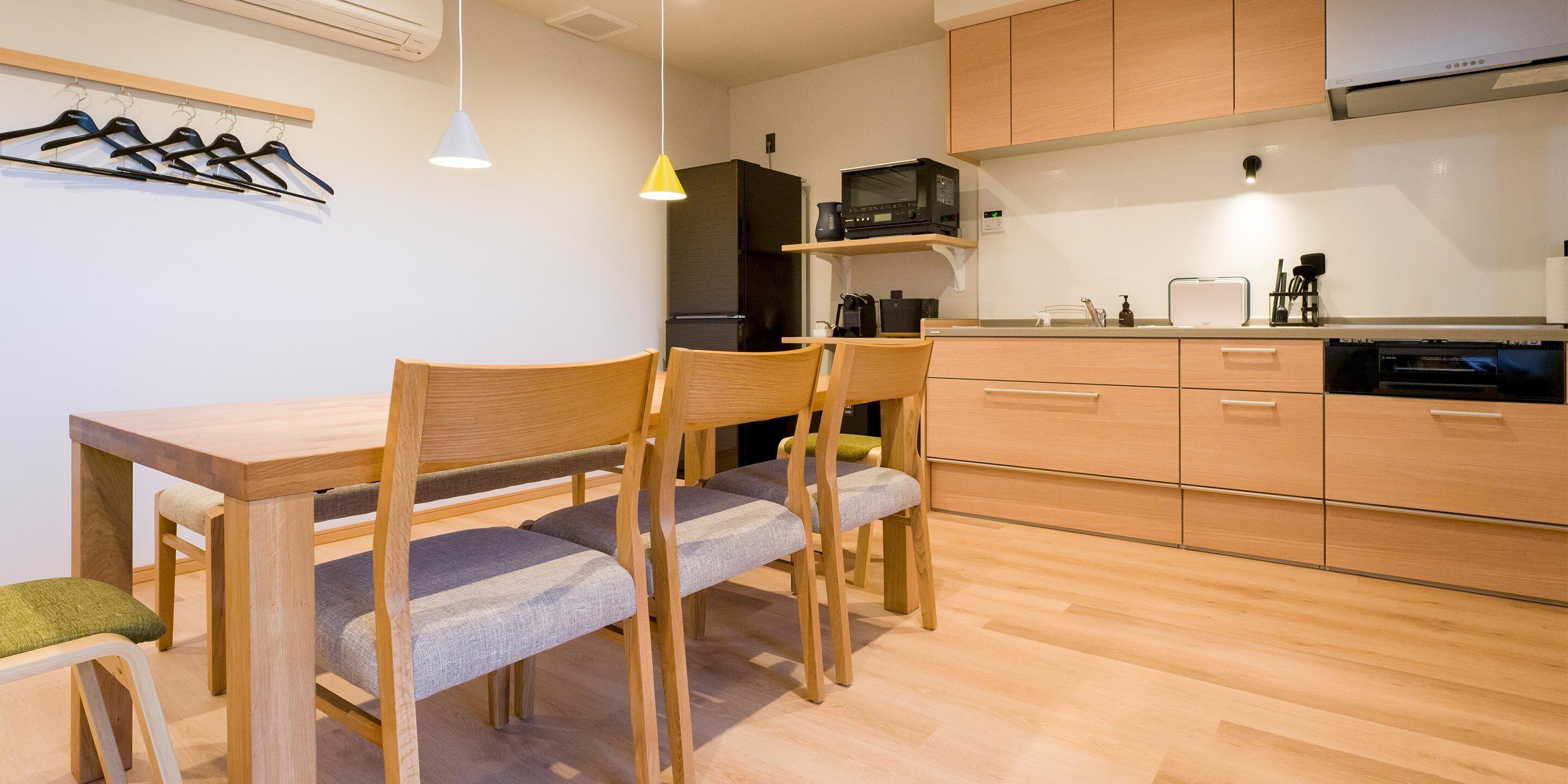 A modern kitchen with wooden cabinets, a dining table with chairs, and a microwave.