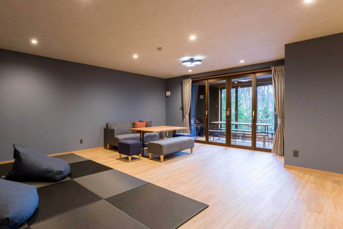 A modern room with a seating area, a table, and a view of the outdoors.