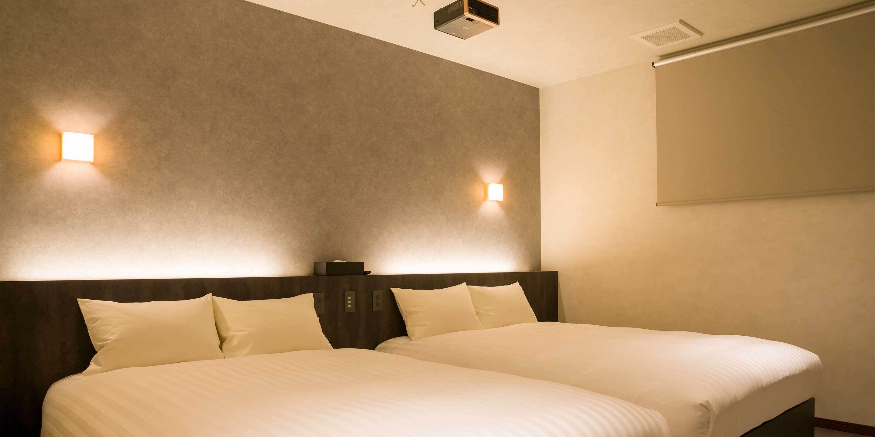 Een hotelkamer met twee bedden, een donker hoofdbord en twee wandlampen.