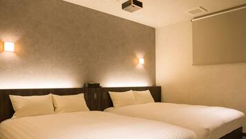 A hotel room with two beds, a dark headboard, and two wall-mounted light fixtures.