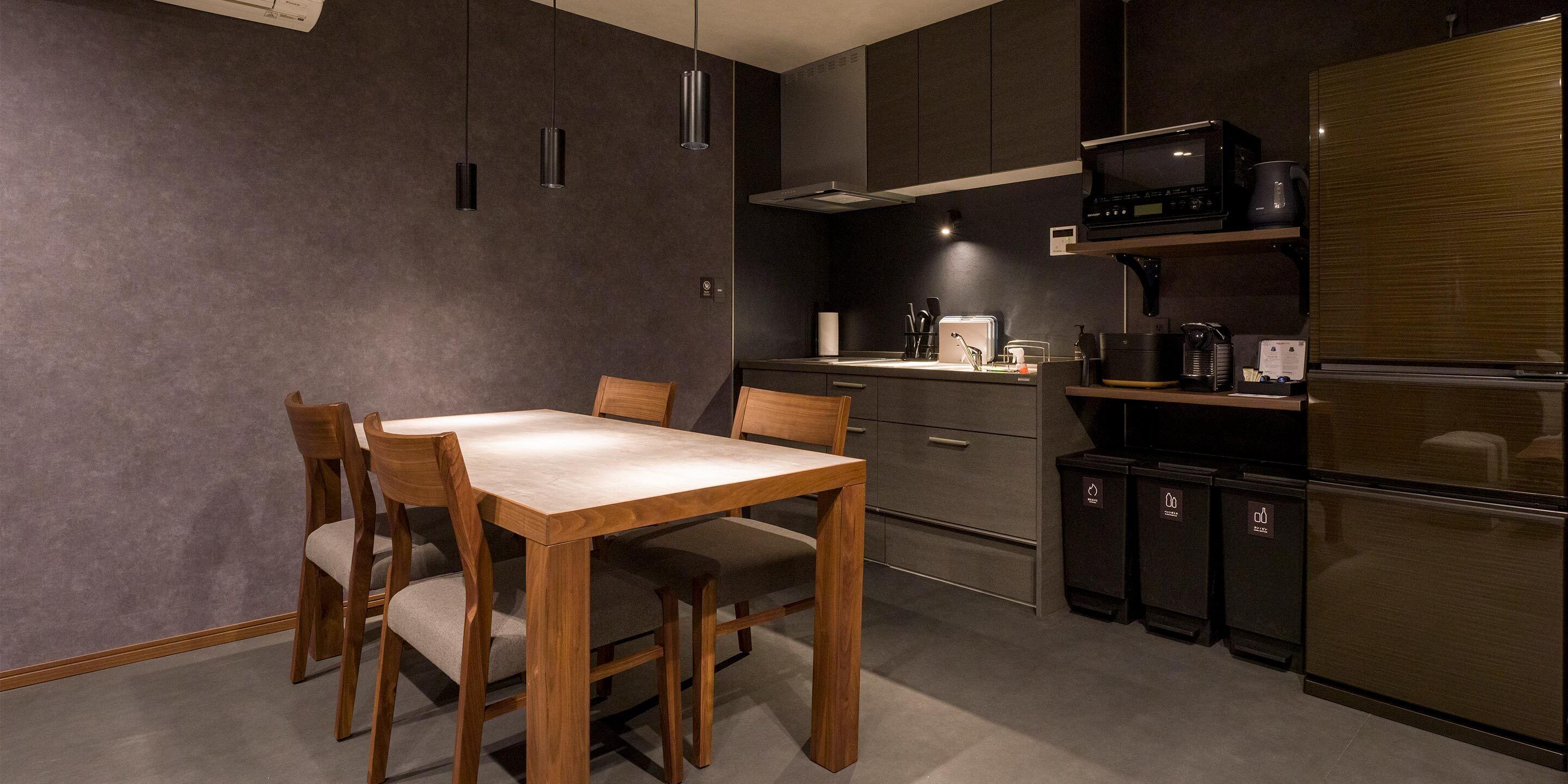A modern kitchen with a wooden dining table and chairs, a built-in oven, and a microwave above the counter.