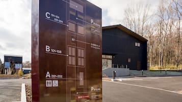 A parking sign with designated spots for EV charging, a disabled parking sign, and a building in the background.