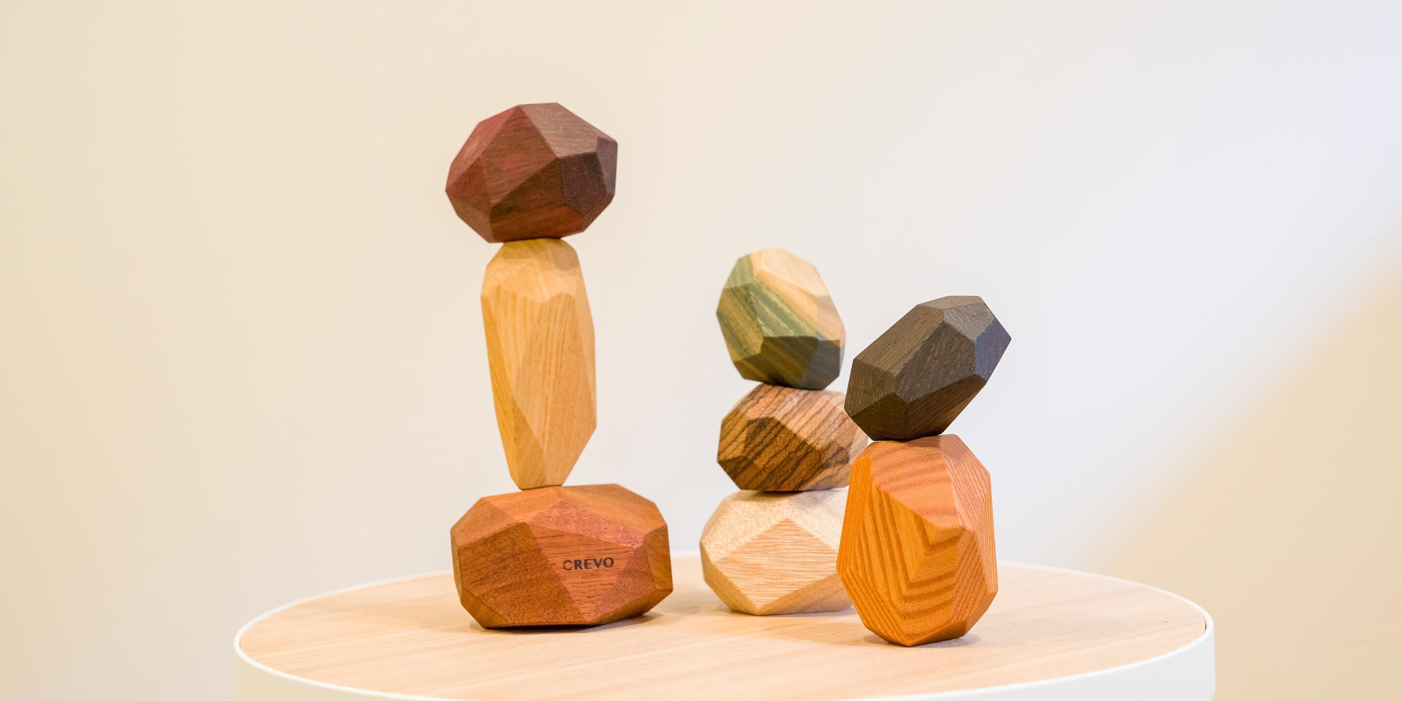 A wooden sculpture with geometric shapes balanced on a circular platform.