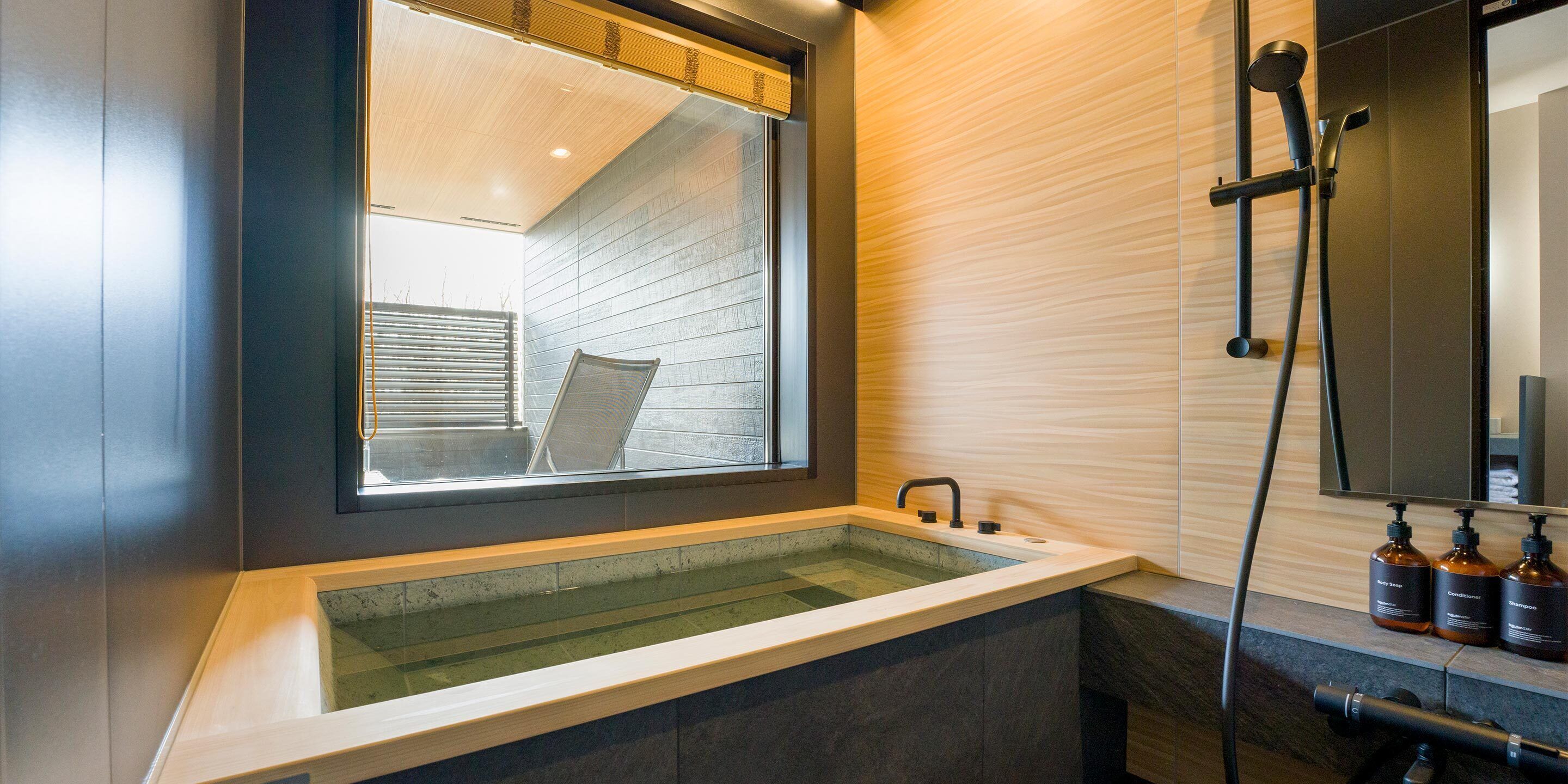 A modern bathroom with a large bathtub, a window, and a shower area.