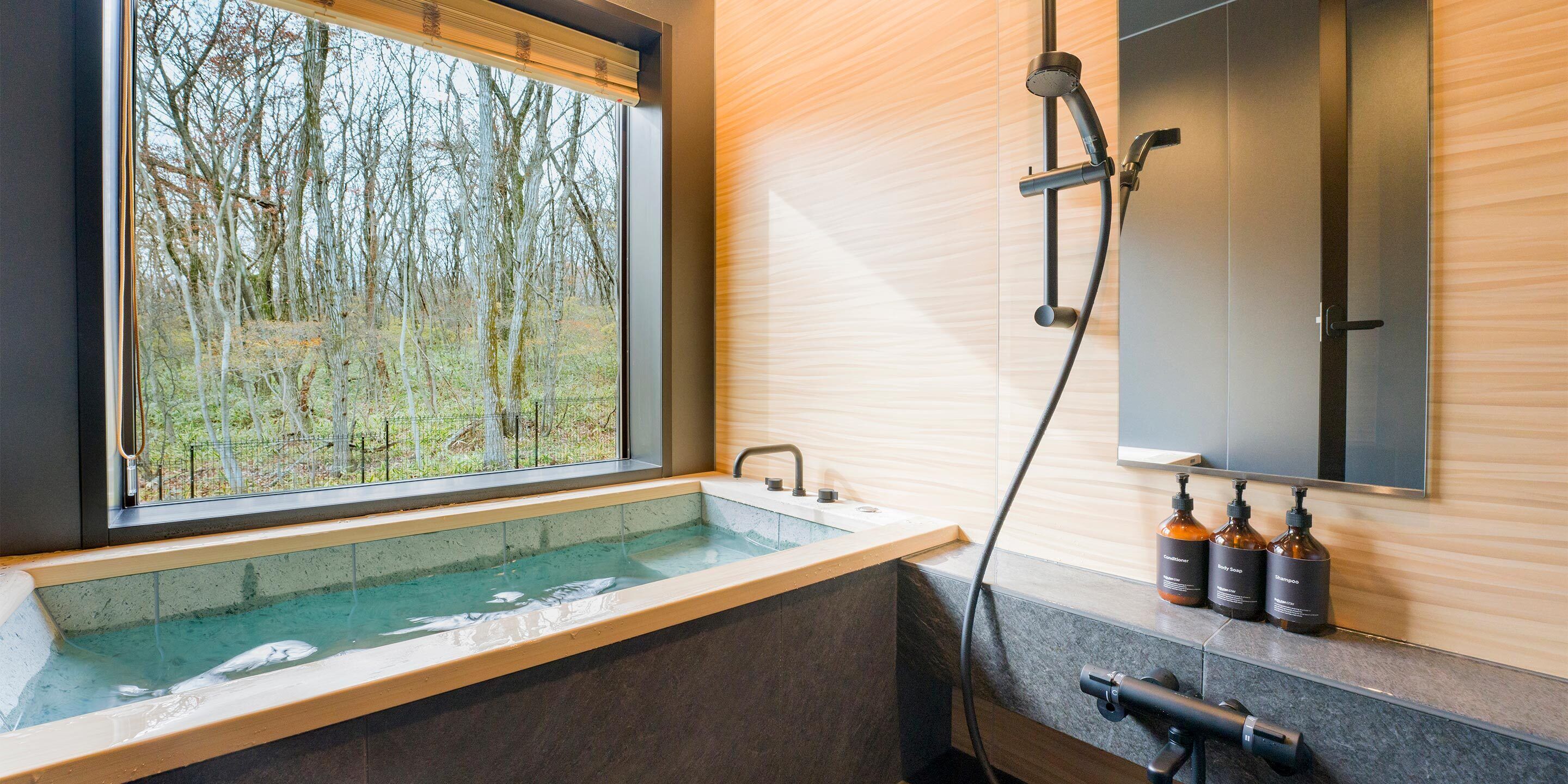 A modern bathroom with a large window, a bathtub, and a shower.