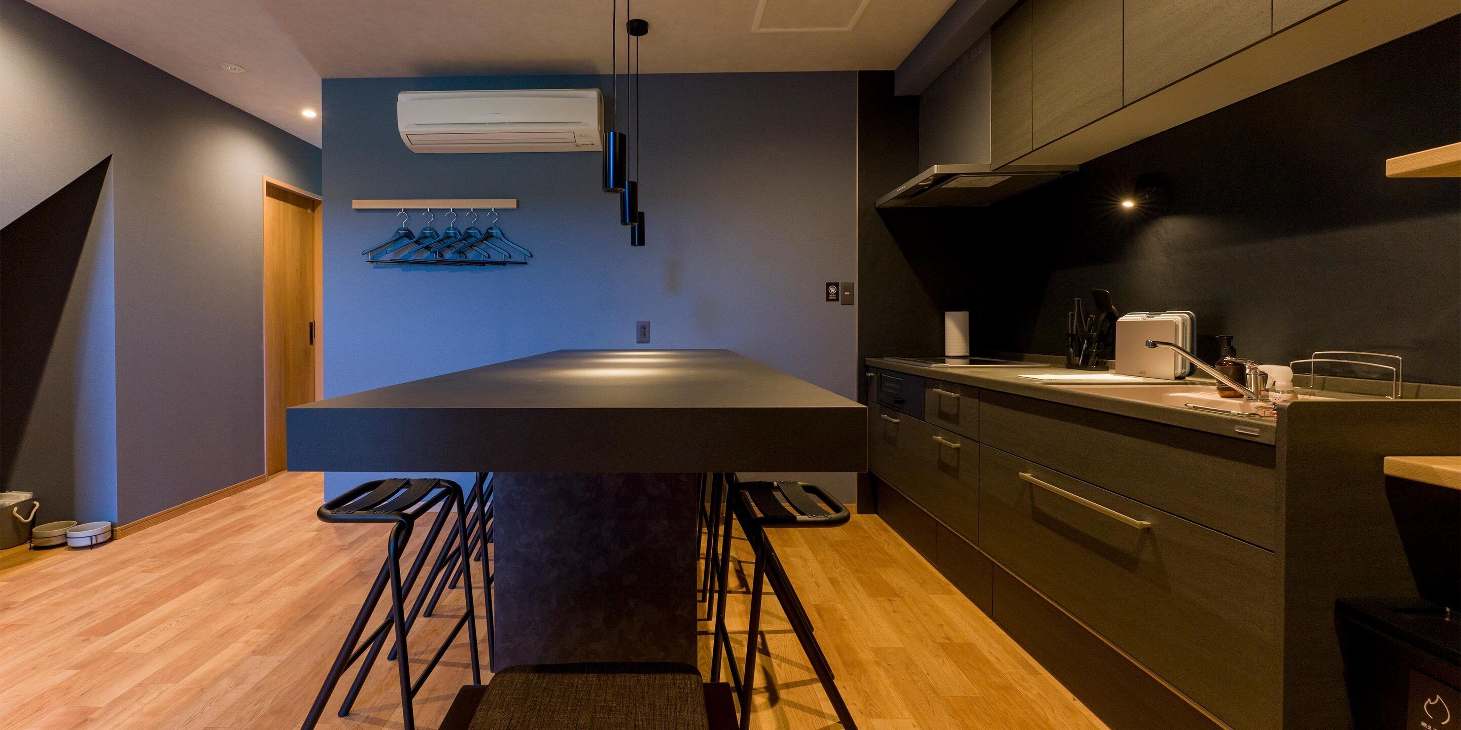 Una cocina moderna con una isla central, taburetes de bar y un perchero.