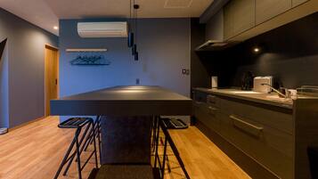 Una cocina moderna con una isla central, taburetes de bar y un perchero.