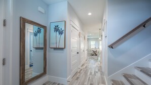 A hallway with wooden flooring, white walls, and a staircase with wooden steps.