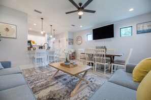 Uma sala de estar moderna com sofá, mesa de centro e área de jantar.