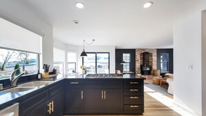 A modern kitchen with a large island, dark cabinetry, and a view of the outdoors. - The Ranch, West Sonoma County (Sebastopol)
