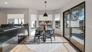 A modern kitchen with a central island, large windows, and a dining area with a round table and chairs. - The Ranch, West Sonoma County (Sebastopol)