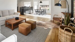 A modern living room with a sofa, coffee table, ottomans, and a dining area with chairs and a table. - The Ranch, West Sonoma County (Sebastopol)