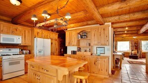 Une cuisine rustique avec des meubles en bois, un îlot central et un sol carrelé en pierre.